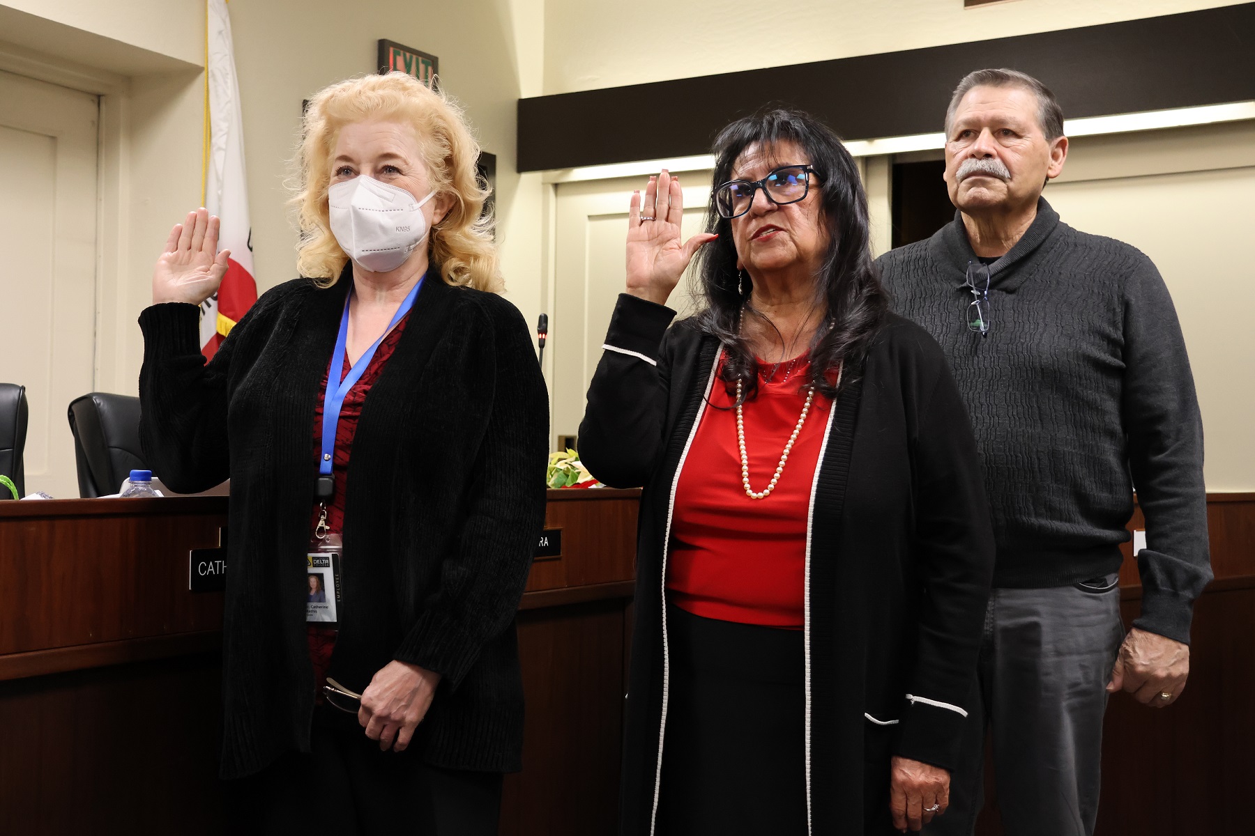 Trustees Catherine Mathis and Janet Rivera take the oath as Trustee Rivera's husband, Rupert, looks on