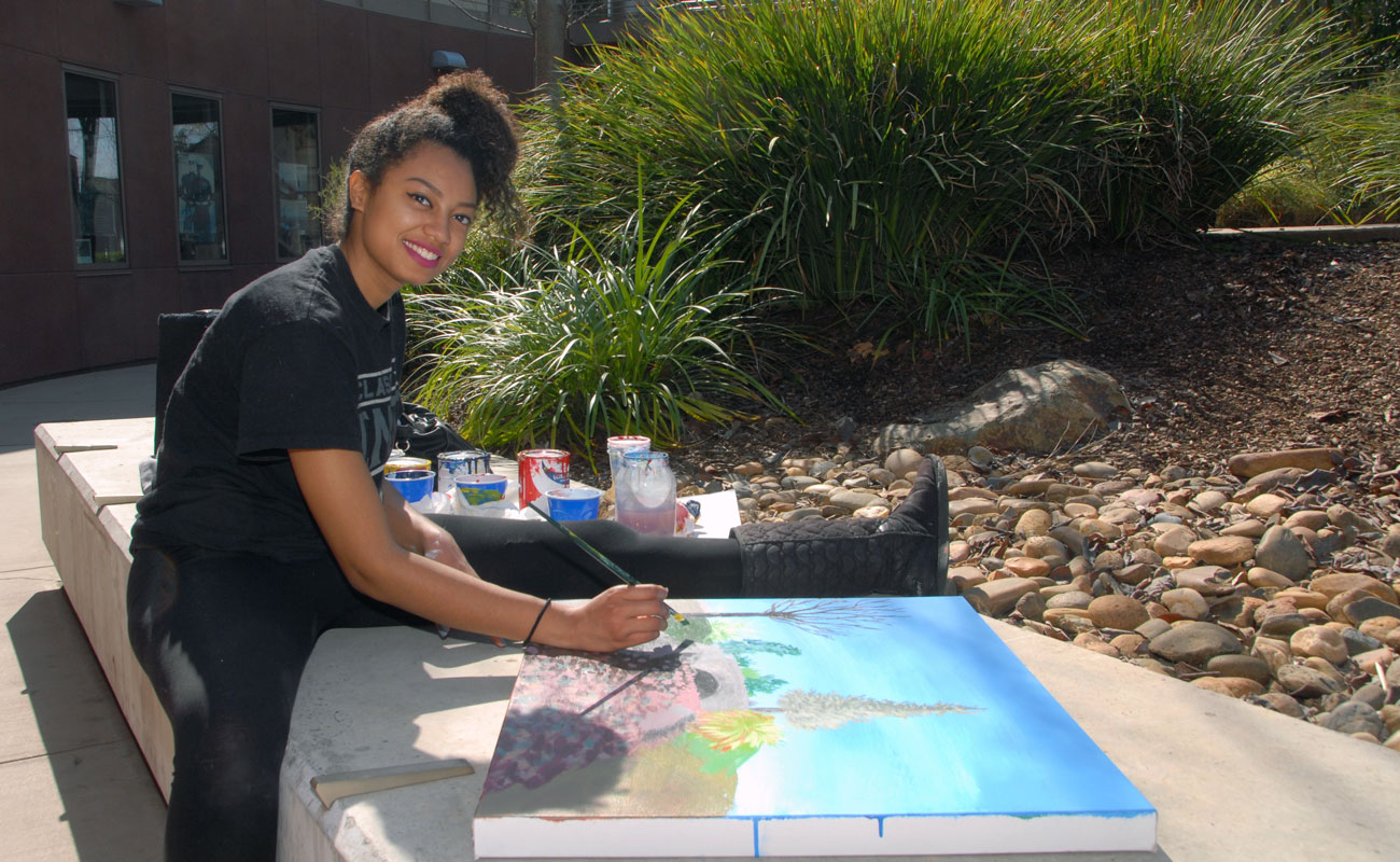 Student artist paints outside at Delta College