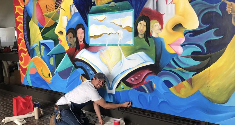 San Joaquin Delta College Professor Mario Moreno touches up a mural that was recently reinstalled on the Stockton campus.